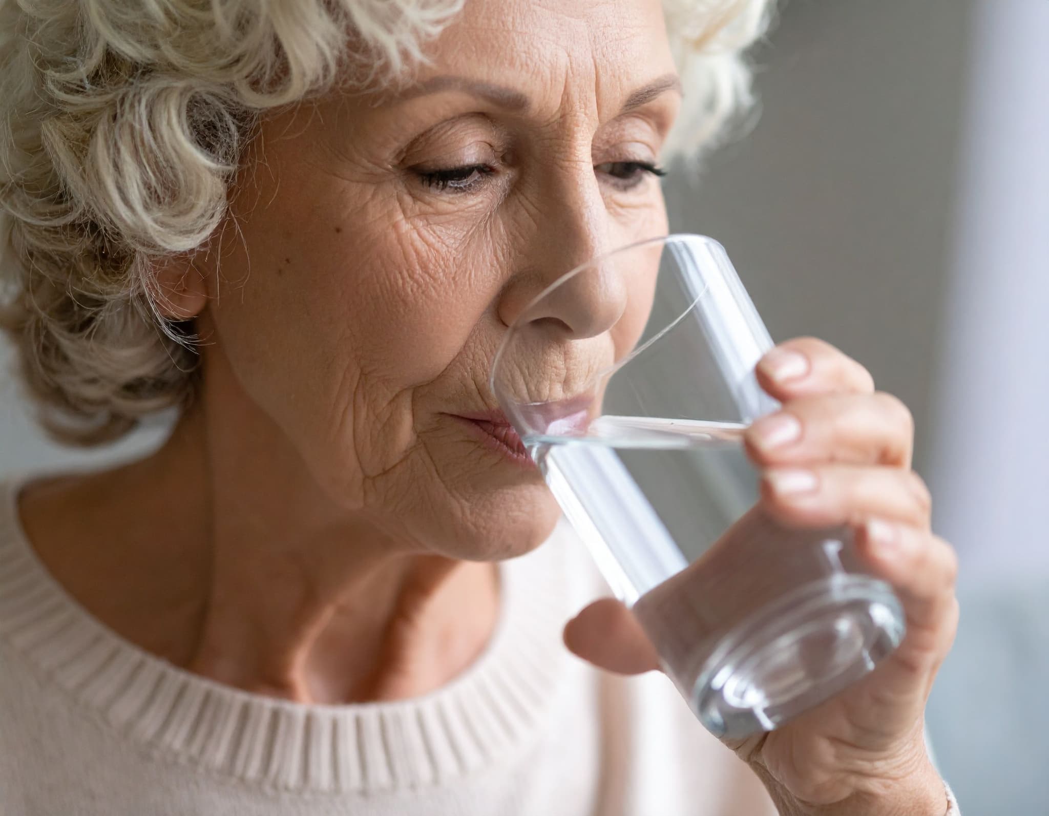 Seniorin trinkt Wasser aus einem Glas