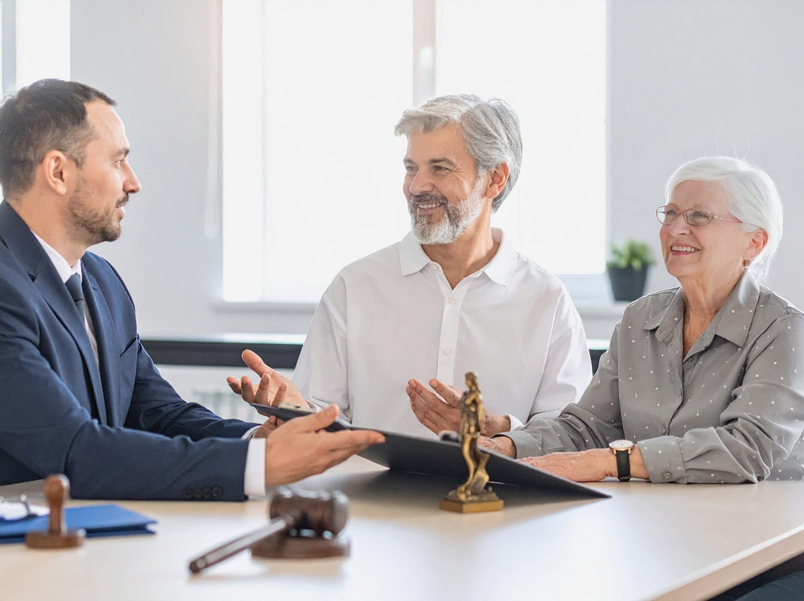 Anwalt berät zwei ältere Personen, die am Tisch sitzen