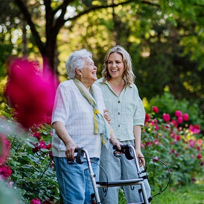 Eine Seniorin geht mit einer Pflegekraft spazieren