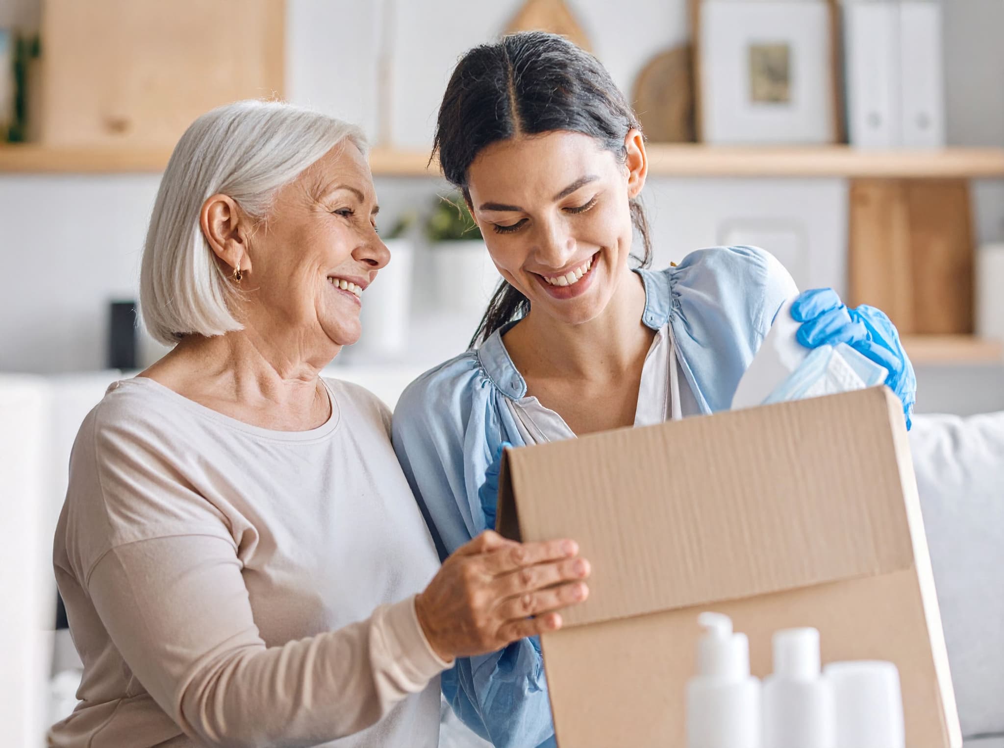 Pflegekraft hilft Seniorin beim auspacken einer Pflegebox